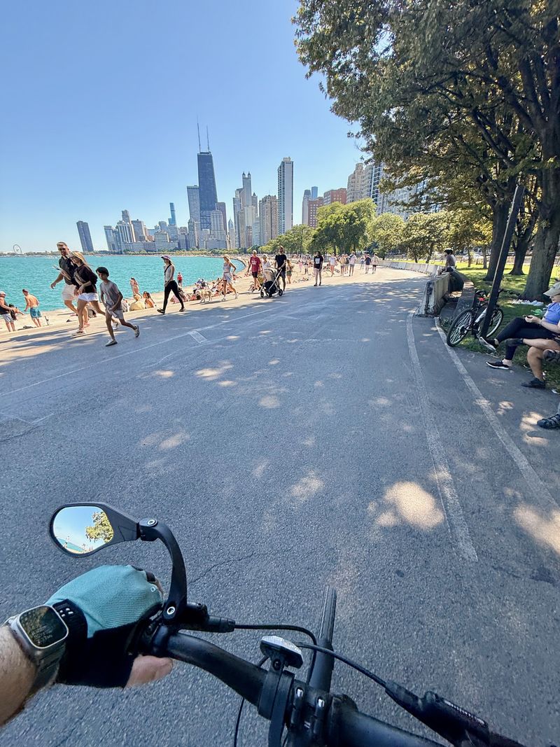A view of the skyline of Chicago and Lake Michigan from behind bicycle handlebars on the Lakefront Trail